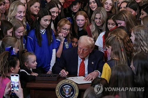 2025년 2월 6일 '여성 스포츠의 날' 에 맞춰 트랜스 여성의 여성스포츠 참여를 금지하는 행정명령에 서명하는 트럼프 대통령. 어린 여성 선수들이 그를 둘러싸고 있다. (사진: 연합뉴스)