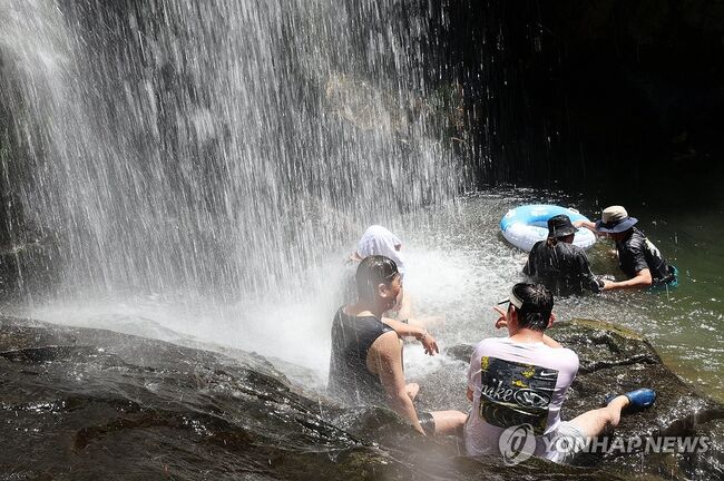 전남 구례군 산동면 수락폭포에서 피서객들이 떨어지는 물줄기를 맞으며 무더위를 식히고 있다. 사진=연합뉴